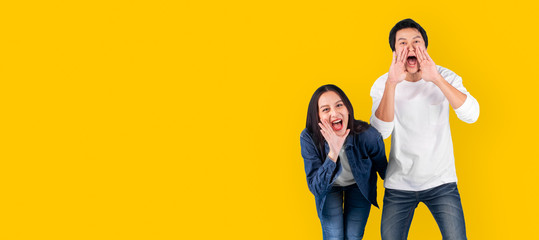 Asian couple man and woman shout and announce with loud over yellow background with copy space