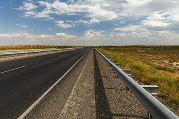 asphalt road in the steppe of Kazakhstan, roadside fencing