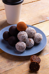 Sweet organic balls with sesame seeds and a cup of coffee on wooden table