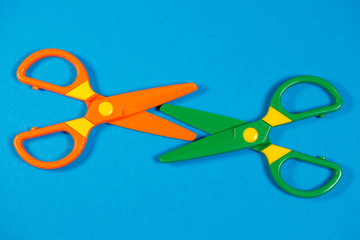 Children's plastic scissors for cutting paper figures on a colored background