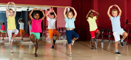 Smiling little boys and girls hands up in class