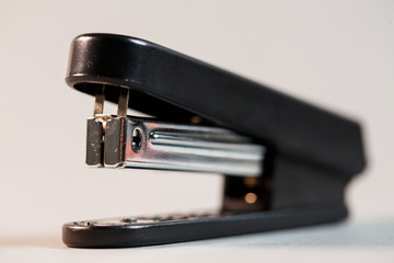 black stapler for fastening papers on a gray background - obrazy, fototapety, plakaty
