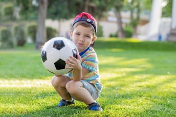 little boy plays football on the football field gives a pass hits the ball runs across the field and scores a goal sports child soccer player trains in the fresh air
