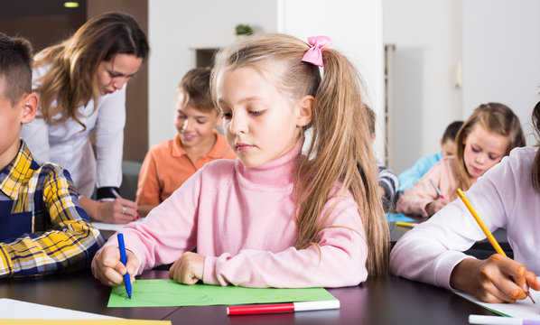 Little children with positive teacher drawing in classroom