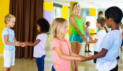 Positive little boys and girls dancing pair dance in the ballet studio
