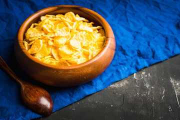 Tasty crispy corn flakes in bowl on the rustic background. Selective focus. Shallow depth of field.