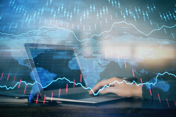 Double exposure of stock market graph with man working on laptop on background. Concept of financial analysis.