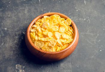 Tasty crispy corn flakes in bowl on the rustic background. Selective focus. Shallow depth of field.