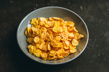 Tasty crispy corn flakes in bowl on the rustic background. Selective focus. Shallow depth of field.