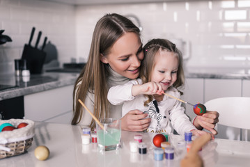 Happy easter. Young mother and her daughter painting Easter eggs. Happy family preparing for Easter.