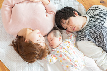 Obraz na płótnie Canvas 赤ちゃんを中心に昼寝をする幸せそうな父と母