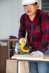 Worker cutting wood with power saw  