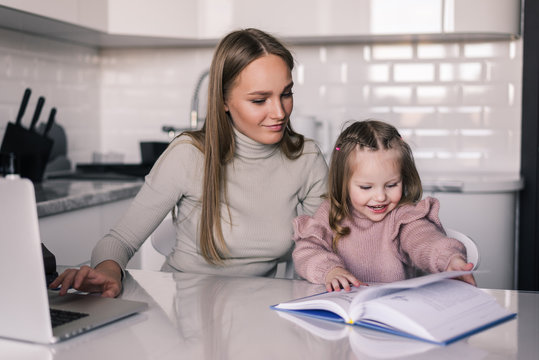 Young mother and child daughter doing homework writing and reading at home