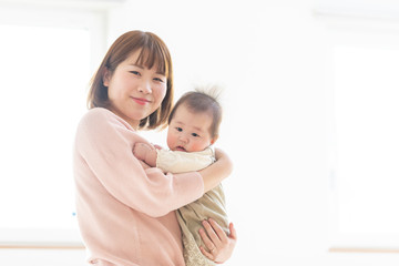 明るい部屋の中で赤ちゃんを抱っこするお母さん