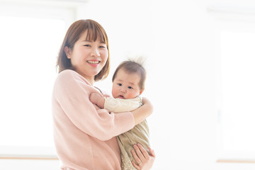 明るい部屋の中で赤ちゃんを抱っこするお母さん