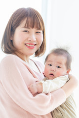 明るい部屋の中で赤ちゃんを抱っこするお母さん