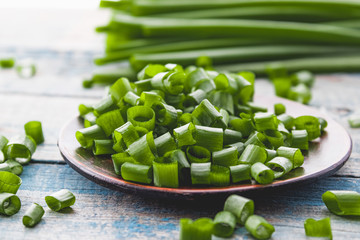 Fresh green onion chopped and lies on a bowl on a background of blue boards.