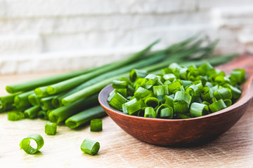Sliced green onion rings in a wooden spoon on the table.
