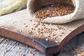 Flax seeds or flaxseed are in a bag on old boards.
