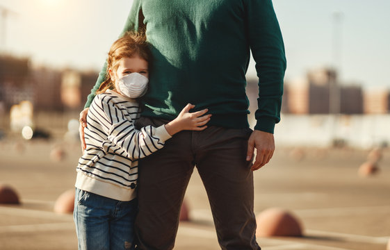 Little girl in medical mask hugs of father.