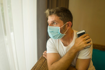 following online news on covid-19 virus pandemic - man with face mask in home quarantine lockdown checking internet information on the contagious disease worried