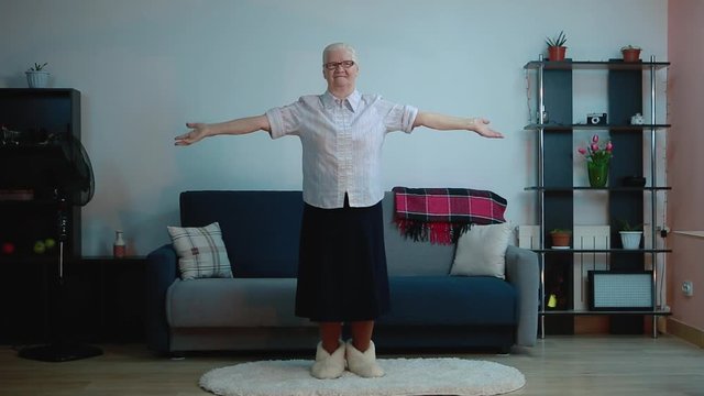 An elderly woman does exercises while in the room