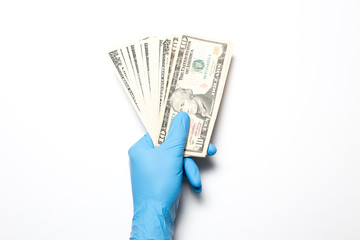 The collapse of the economy due to the coronavirus. Male hand on a white background in medical gloves holds dollars.