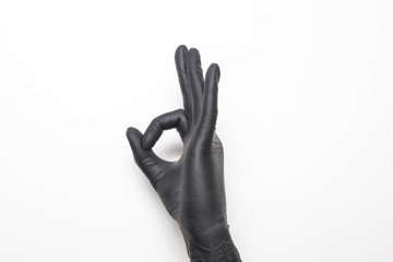Medical glove in black on a white background. Hand showing okay sign.