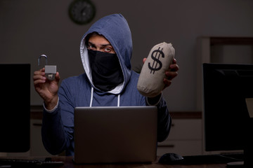 Male hacker hacking security firewall late in office