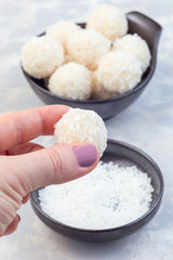 Making healthy raw paleo energy balls with shredded coconut, almond flour, coconut butter and sweetener, vertical