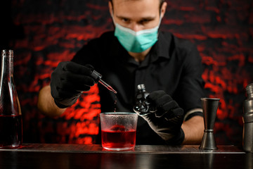 Professional barman carefully adds ingredient to cocktail