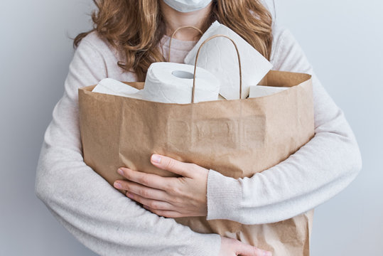 Buying panic for home quarantine due to coronavirus. Stay at home for covid-19 protection concept. Woman hold a shopping bag with tissue toilet paper rolls