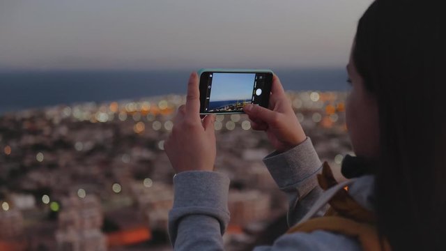 Woman take picture of the sea by smartphone in the evening. Woman stay on top of the mountain and looking Into Horizon, slow motion, 4k