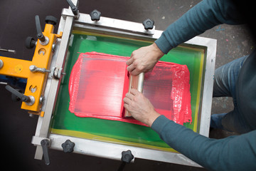 Silk screen printing. Serigraphy. Color paints and fabric. Plastisol paint and squeegee.