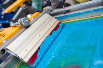 Silk screen printing. Serigraphy. Color paints and fabric. Plastisol paint and squeegee.