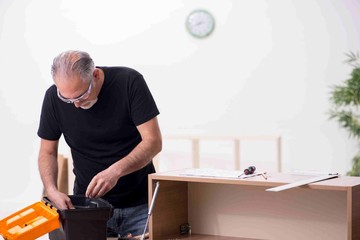 Old male carpenter working indoors