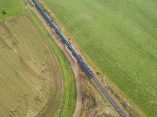 Fototapeta na wymiar Aerial view of Swiss commuter train. Railroad tracks through agricultural farmland and fields.