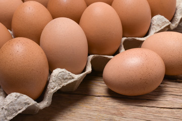 Chicken eggs in carton box on wooden table.