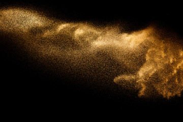 Golden sand explosion isolated on black background. Abstract sand cloud.Sandy fly wave in the air.