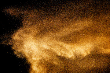 Golden sand explosion isolated on black background. Abstract sand cloud.Sandy fly wave in the air.