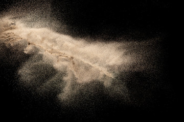 Brown colored sand splash.Dry river sand explosion isolated on black background. Abstract sand...