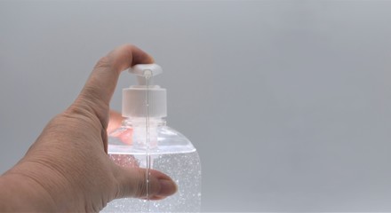 A female hand presses a dispenser of antiseptic hydroalcoholic gel, indicated for the prevention of bacterial and viral diseases.