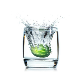 Ripe green watermelon drops in a glass goblet with water. Isolated on white background