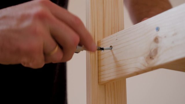 man screws a shelf. Screw and screwdriver. Male hand. Houseworker. Close-up.