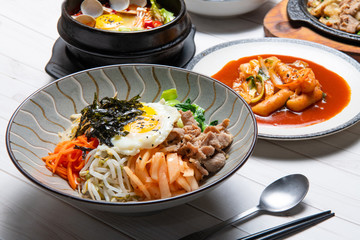 Bibimbap is served as a bowl of warm white rice topped with vegetables or kimchi and chili pepper paste and egg and sliced meat