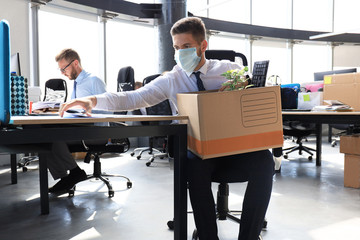 Dismissal employee in an epidemic coronavirus. Sad dismissed worker are taking his office supplies...