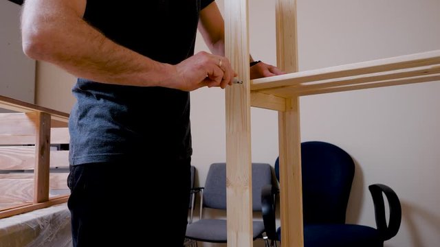man screws a shelf. Screw and screwdriver. Male hand. Houseworker