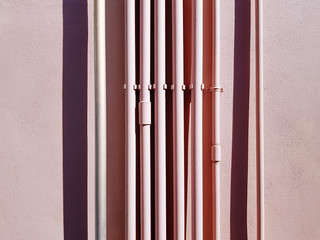 Set of Pink Vertical Water Piping Against Pink Wall