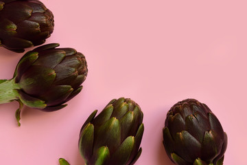 fresh artichokes on a pink background. layout top view. concept of seasonal vegetables. delivery of fresh vegetables