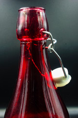 red glass bottle with stopper isolated on a black background